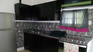 Une cuisine avec des meubles de couleur noire, un évier en acier inoxydable et une cuisinière à gaz.