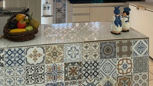 A kitchen with patterned tiles, a fruit basket, a microwave, and a decorative figure. - Recanto Minduba (Japaratinga)