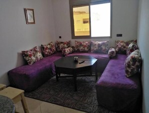 A living room with a sofa set, a coffee table, and a window with blinds.