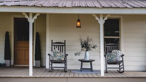 Ein zweistöckiges Haus mit Veranda, Steinmauer und einem kleinen Fenster.