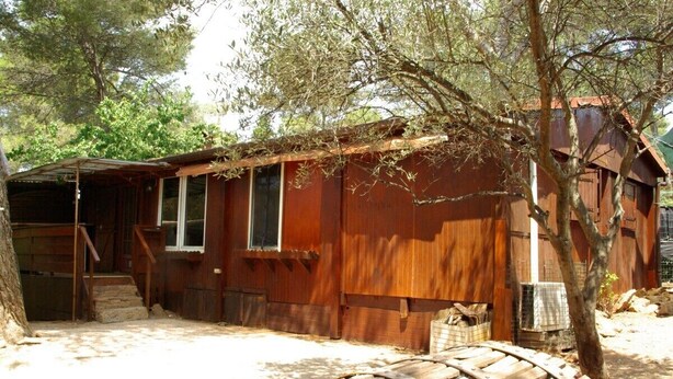 A rustic wooden cabin with a covered porch and a wooden wheelbarrow. - Maison six Couchages à Proximité de la Mer. Location Aout, Septembre 2024 (Le Castellet)