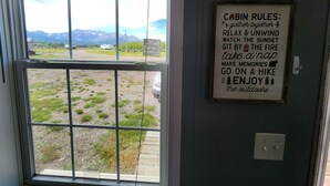 Eine Hütte mit Blick auf Berge durch ein Fenster, ein Schild mit Hüttenregeln und eine Steckdose an der Wand.