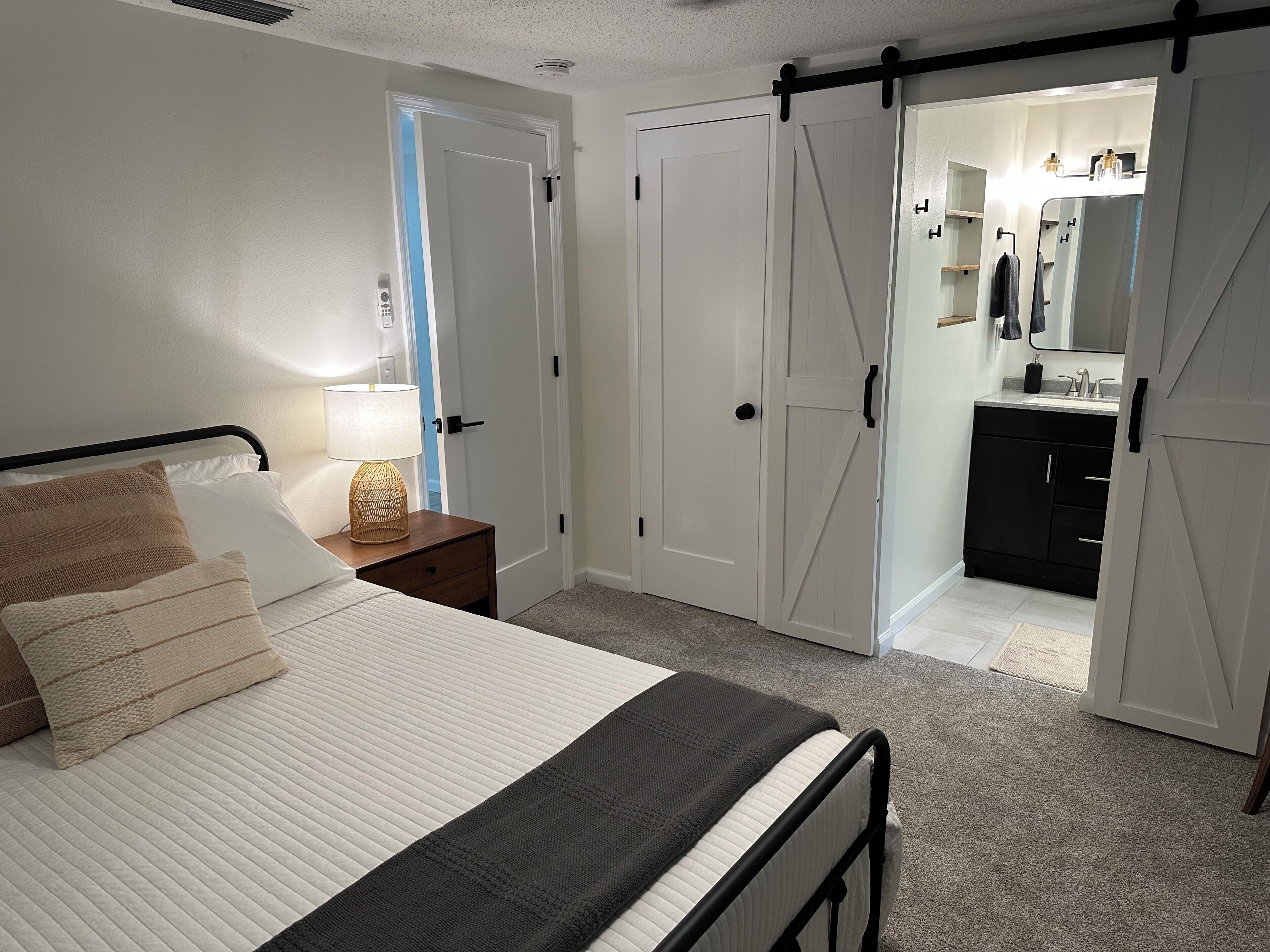 A bedroom with a bed, bedside table, lamp, and a sliding closet door leading to a bathroom.