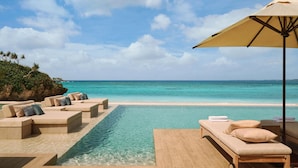 A poolside area with lounge chairs and an umbrella, overlooking a clear blue ocean. - Rosewood Miyakojima (Miyakojima)