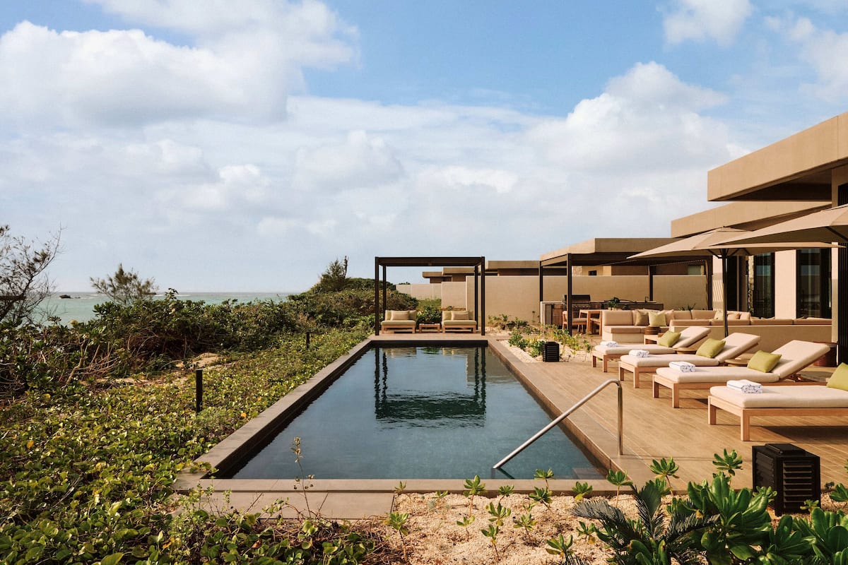 Un área de piscina moderna al aire libre con sillas de descanso y vistas al mar.