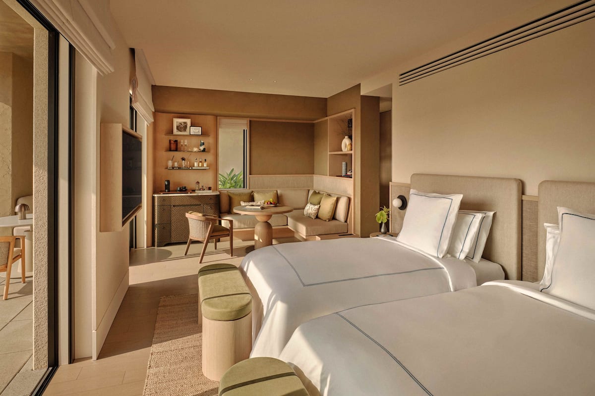 Una habitación de hotel moderna con una cama grande, una zona de estar con una mesita y una kitchenette.