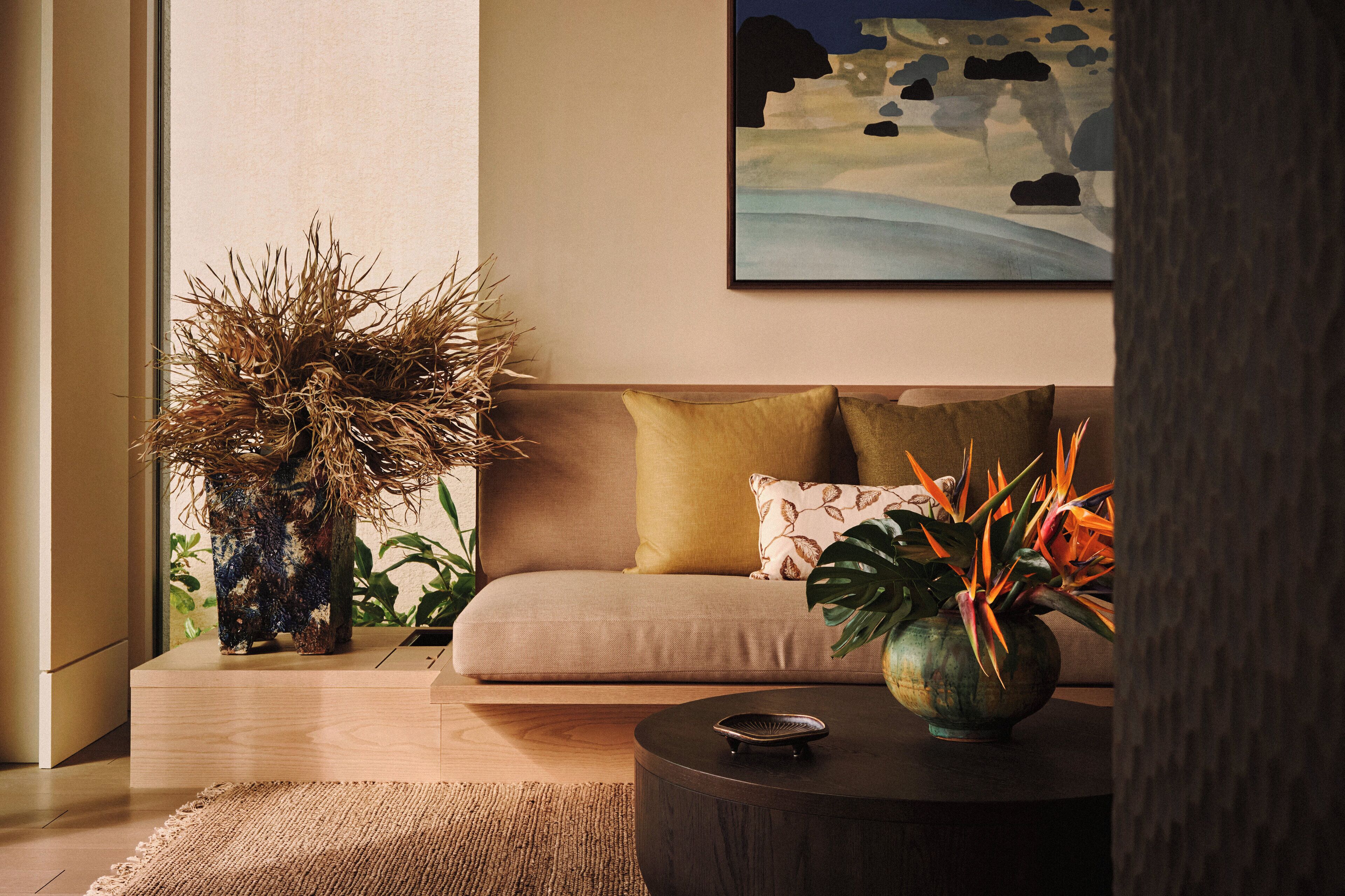 A modern living room with a sofa, a round coffee table, and decorative plants.
