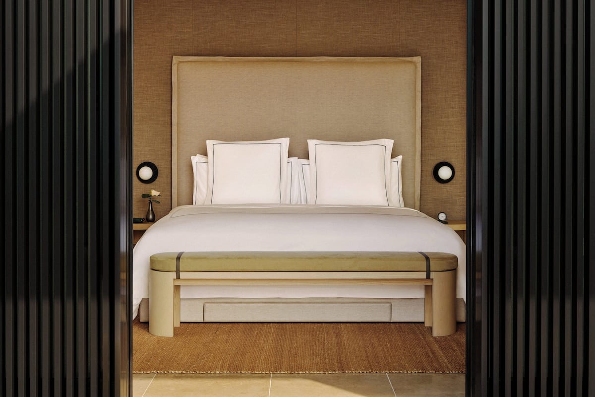 Una habitación de hotel moderna con una cama grande, una mesita de noche y un tocador.