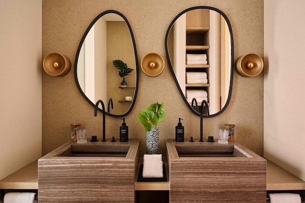 Un baño con dos lavamanos, un espejo y un florero con una planta.