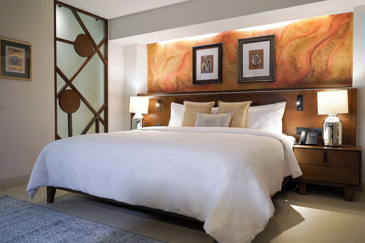 A hotel room with a large bed, two bedside tables with lamps, and a wall with framed artwork.