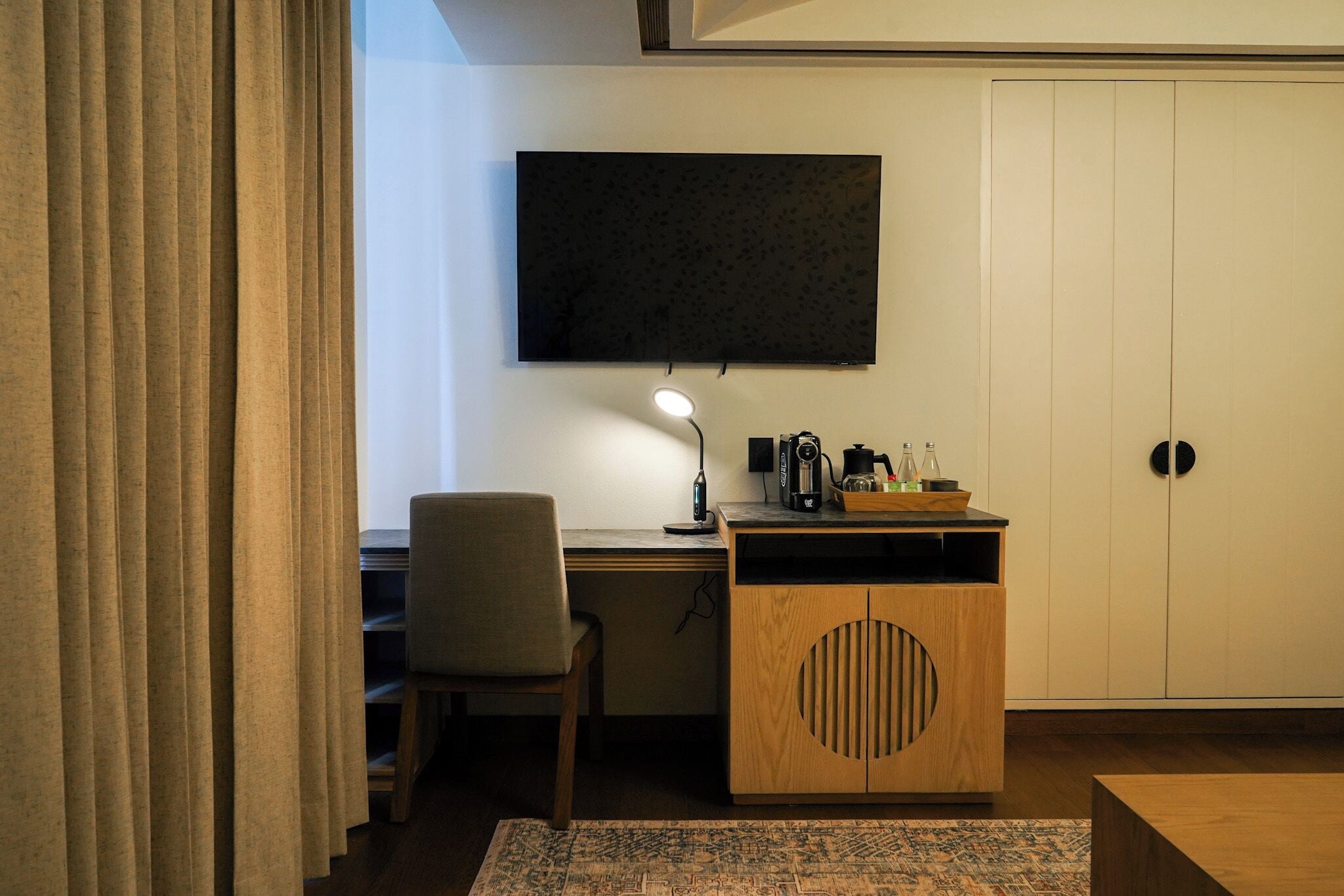 A room with a desk, chair, television, and a cabinet with a circular cutout.