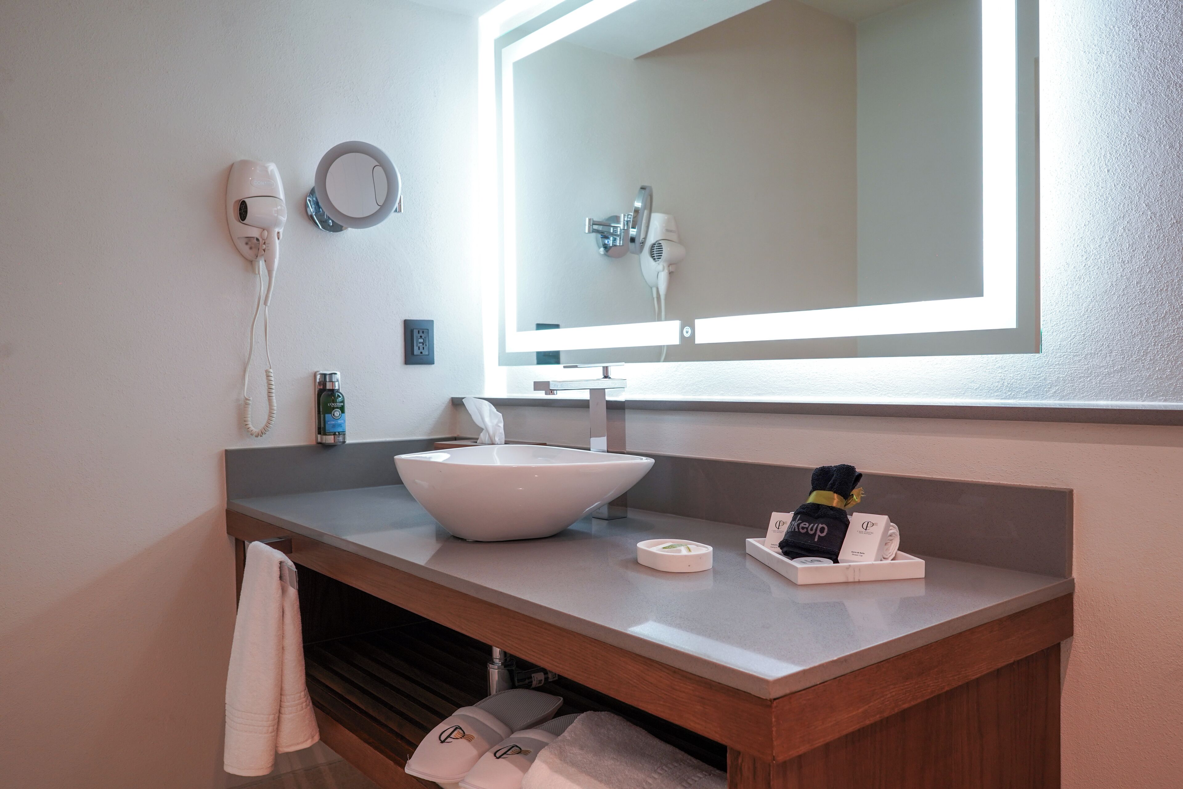 A bathroom with a white sink, a mirror, a hairdryer, and a towel rack.