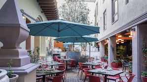 An outdoor dining area with tables and chairs, a large umbrella, and potted plants. - Casa Postal Hotel Boutique (Querétaro)