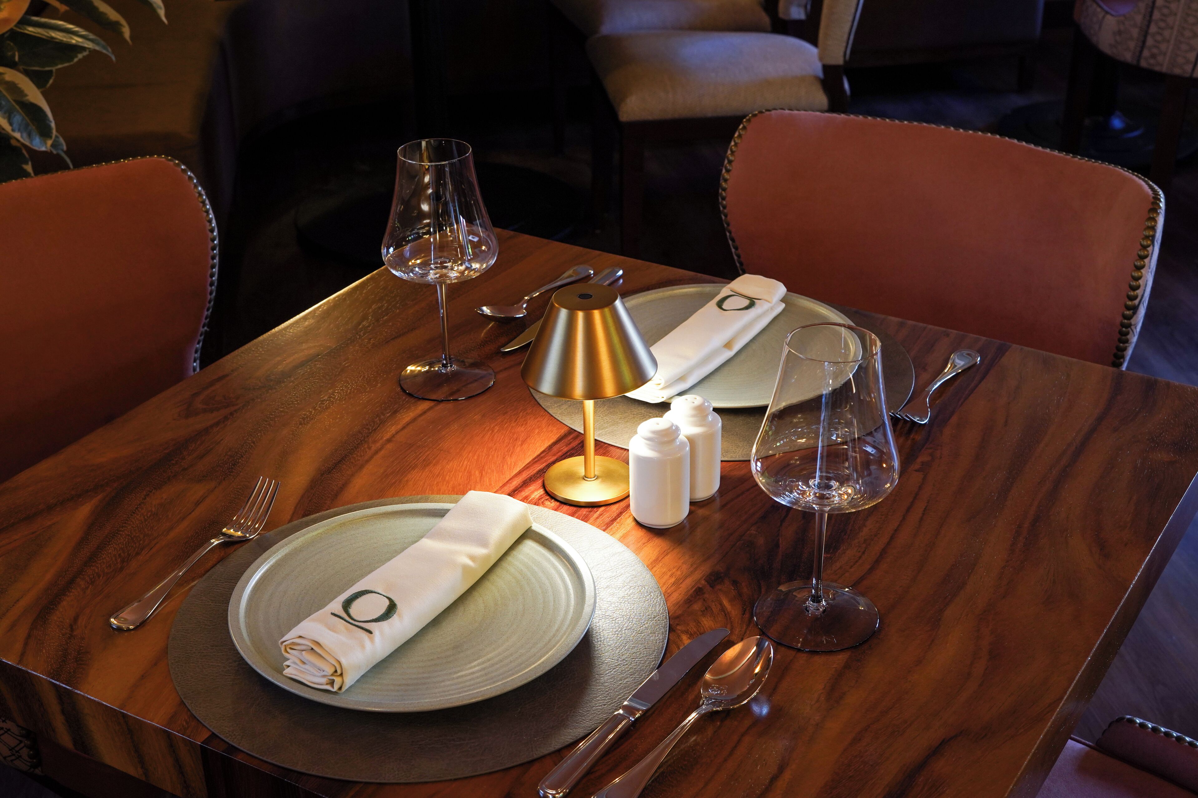 Une table dressée avec une serviette pliée, une assiette, des couverts et un verre.