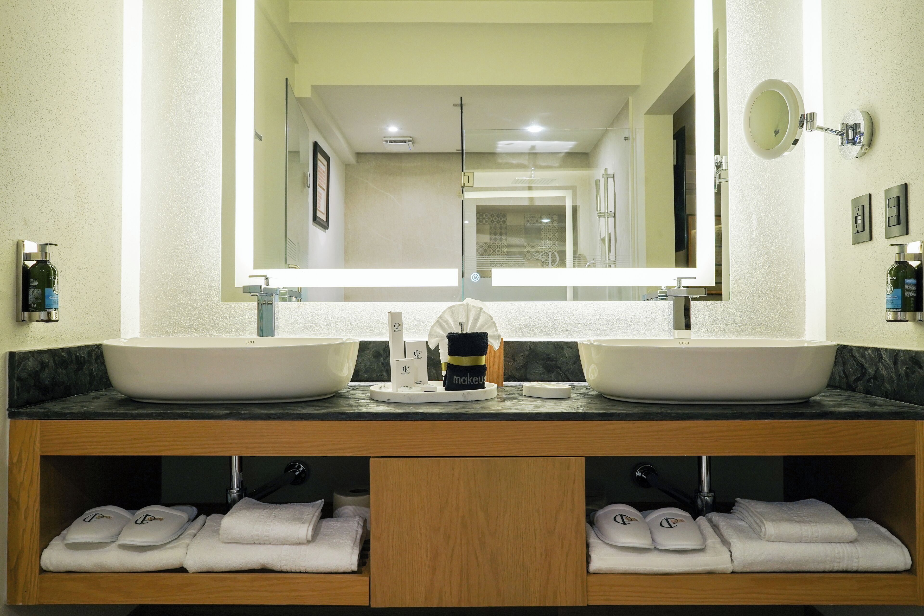 Une salle de bain avec deux lavabos, un grand miroir et un meuble-lavabo avec des serviettes.
