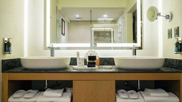 A bathroom with two sinks, a large mirror, and a vanity with towels.