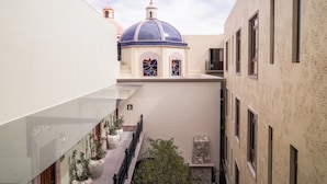 A courtyard with a blue-domed building, potted plants, and a stone bench. - Casa Postal Hotel Boutique (Querétaro)