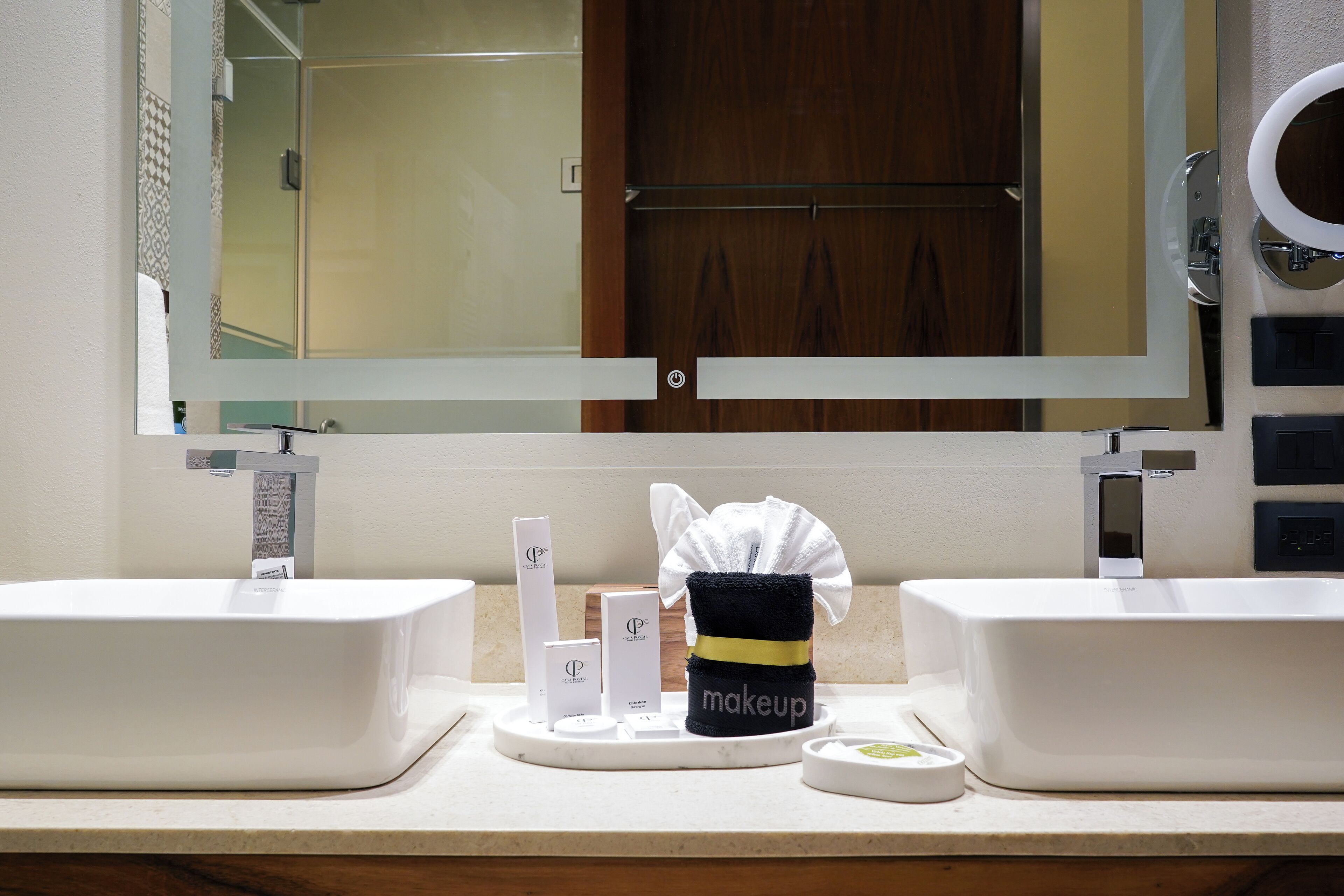 A bathroom with two sinks, a mirror, and a vanity area with toiletries.