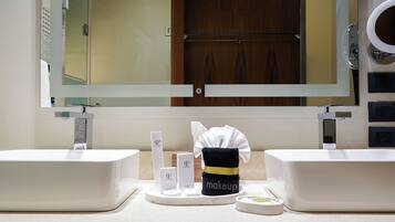 A bathroom with two sinks, a mirror, and a vanity area with toiletries.
