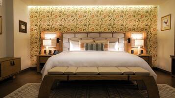 A large bed with a headboard, two bedside lamps, and a patterned wallpaper.