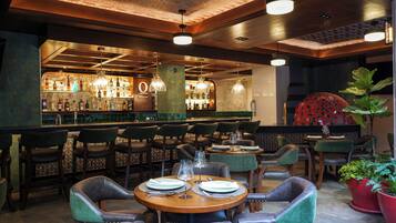 A restaurant with a bar area, wooden tables, and chairs.
