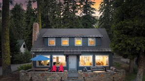 A two-story house with a stone foundation, a chimney, and a porch with outdoor seating. - West Shore Lake House by Avantstay Ski Cabin w/ Backyard Sledding Hill! (Homewood)