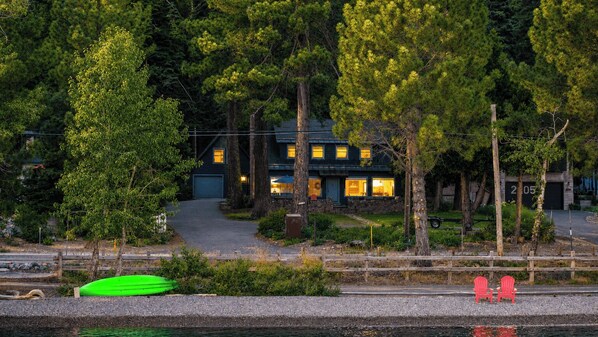 A house with a dock, a green kayak, and red chairs by the water. - West Shore Lake House by Avantstay Ski Cabin w/ Backyard Sledding Hill! (Homewood)
