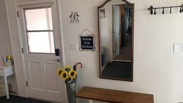 A room with a white door, a bench, a mirror, and a welcome sign.