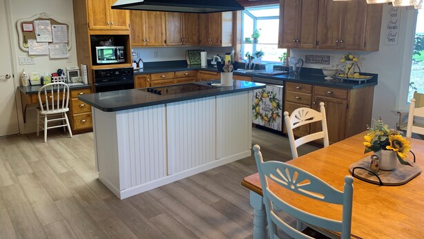 Cocina moderna con armarios de madera, una isla central e iluminación colgante.