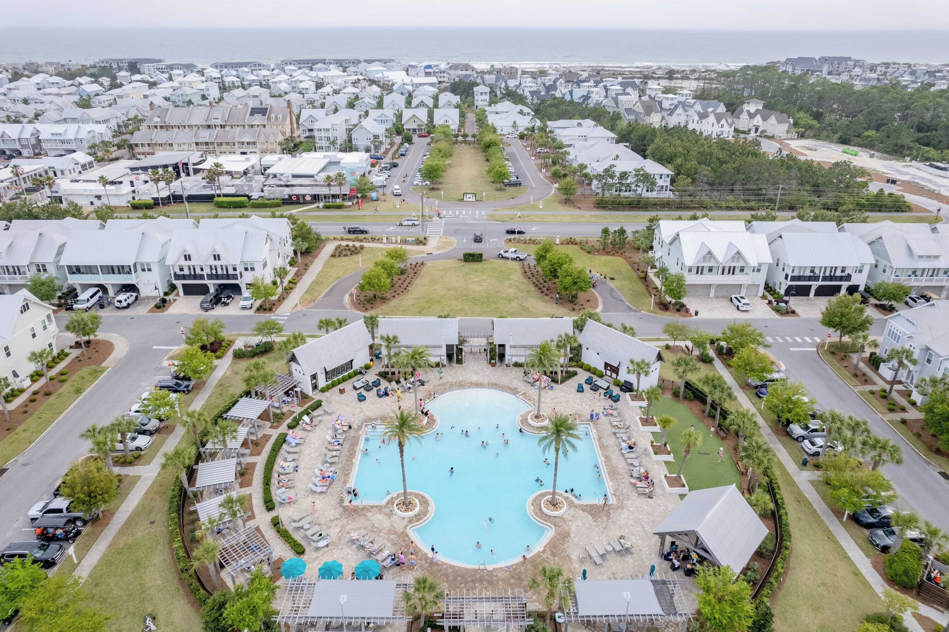 Un quartiere residenziale con una piscina centrale circondata da case, strade e vegetazione.