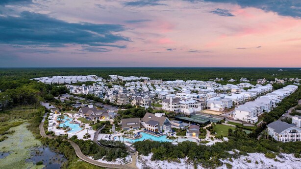 Luftaufnahme eines Küstenresorts mit mehreren Gebäuden, einem Pool und umliegender Bepflanzung.