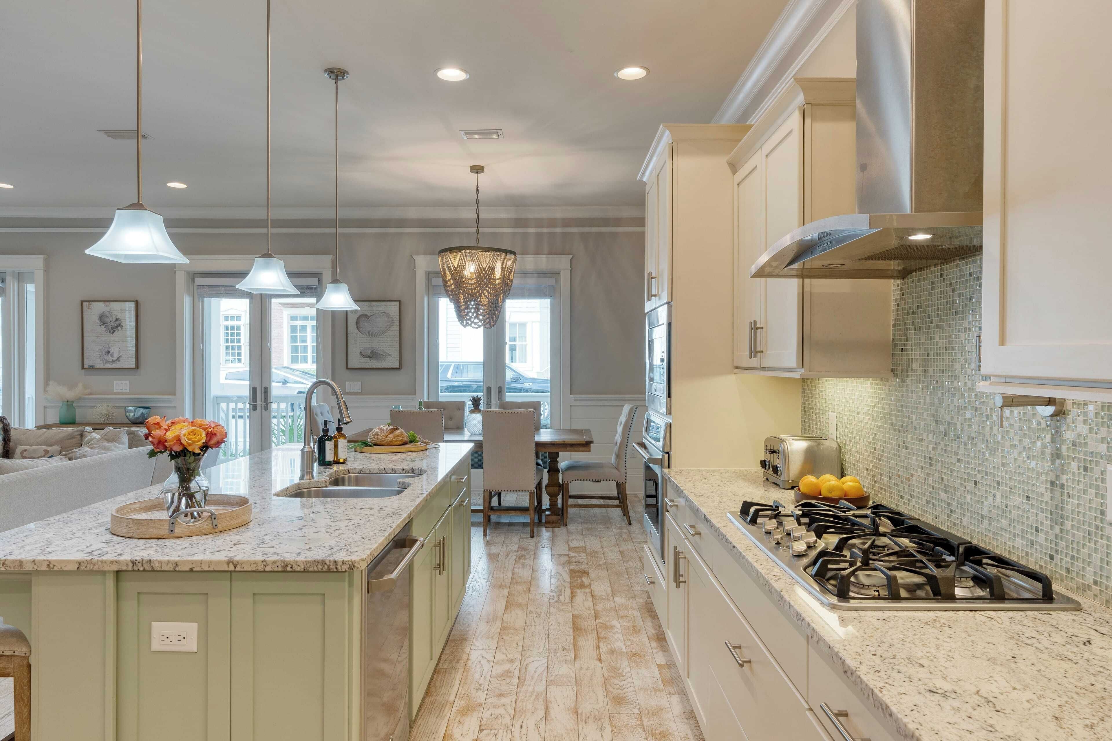 A modern kitchen with a central island, pendant lighting, and a gas stove.