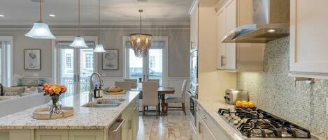 A modern kitchen with a central island, pendant lighting, and a gas stove.