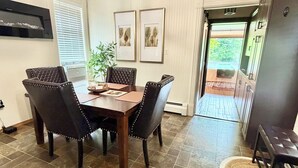 Un comedor con una mesa, sillas, una planta y obras de arte en la pared.