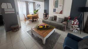 Een woonkamer met een eethoek, een bank, een salontafel en een kleine kerstboom.