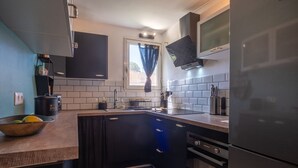 Een kleine keuken met een zwart aanrechtblad, een ingebouwde oven en een roestvrijstalen koelkast.
