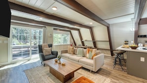 A spacious living area with a large window, a sofa, a coffee table, and a kitchen area with stools. - Speckled by Avantstay Modern Interior, 0.5mi to Lake! (Kings Beach)