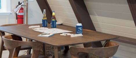 A wooden table with Scrabble tiles, two bottles of beer, and a can of beer.