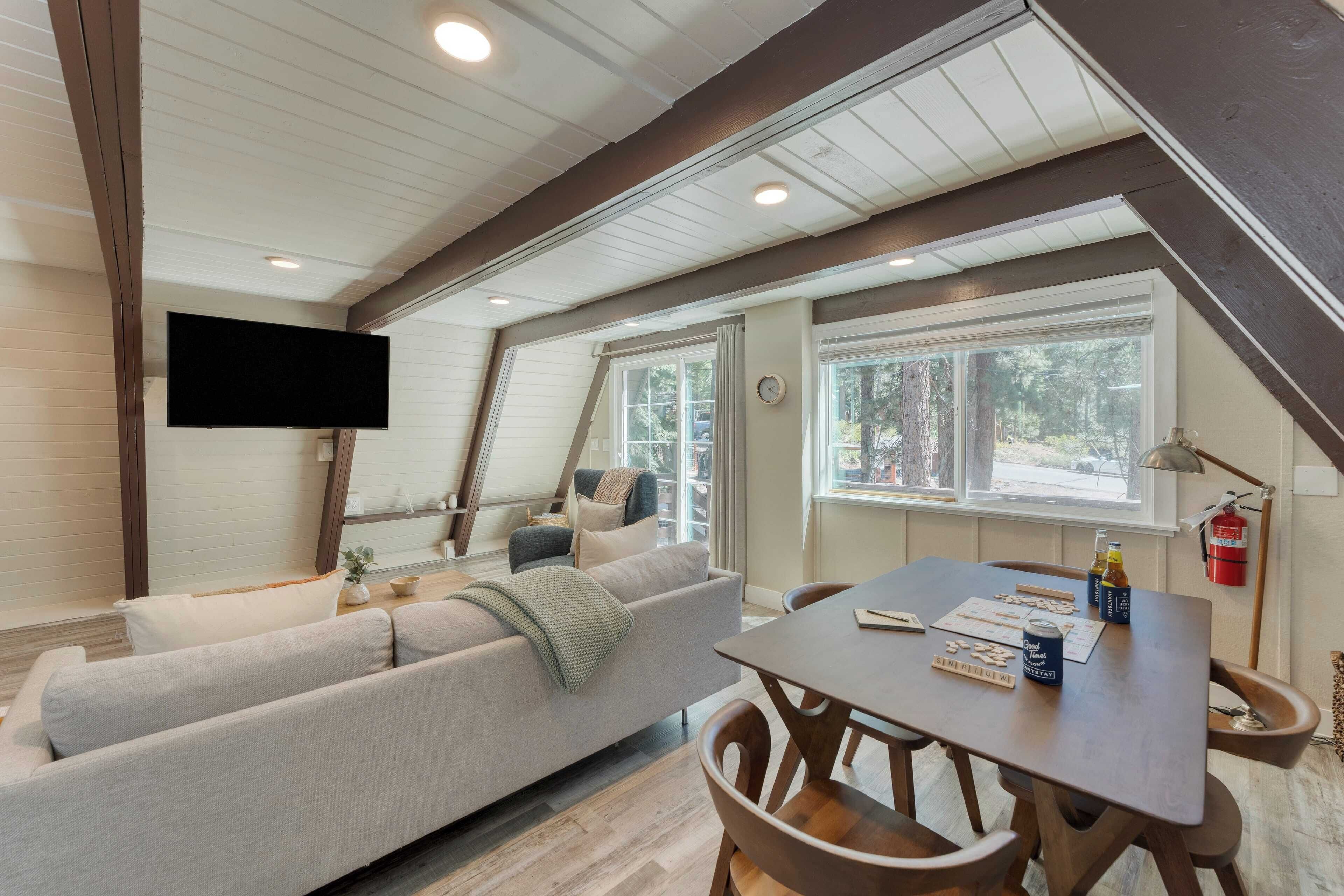 A cozy living room with a sofa, a dining table, and a flat-screen TV mounted on the wall.