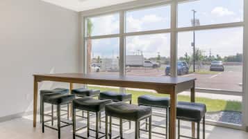 A room with a large window, a wooden table, and six black bar stools.