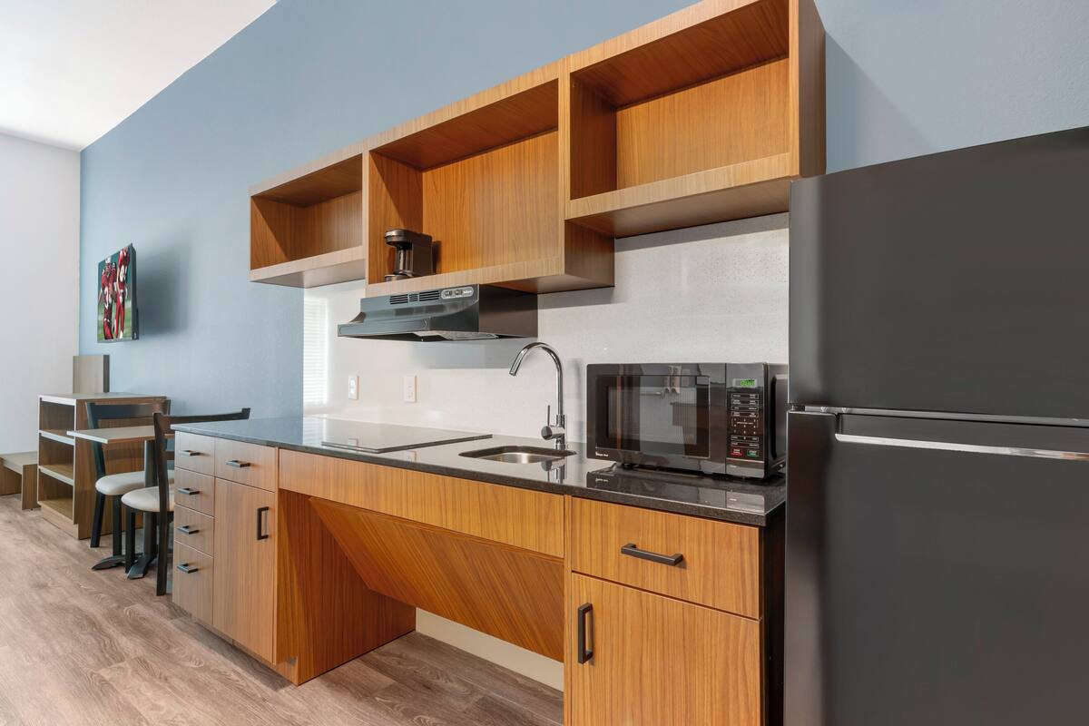 Una cocina moderna con armarios de madera, un refrigerador negro, un microondas y una cafetera.