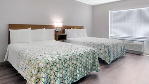 A hotel room with two beds, a nightstand, a lamp, and a window with blinds. - HomeTowne Studios by Red Roof Tampa - Airport (Tampa)