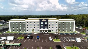 A multi-story hotel with a central entrance and a parking lot. - HomeTowne Studios by Red Roof Tampa - Airport (Tampa)