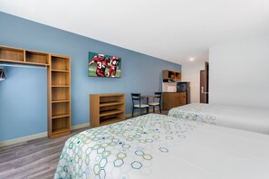 A hotel room with two beds, a wardrobe, a desk, a chair, and a television on the wall. - HomeTowne Studios by Red Roof Tampa - Airport (Tampa)