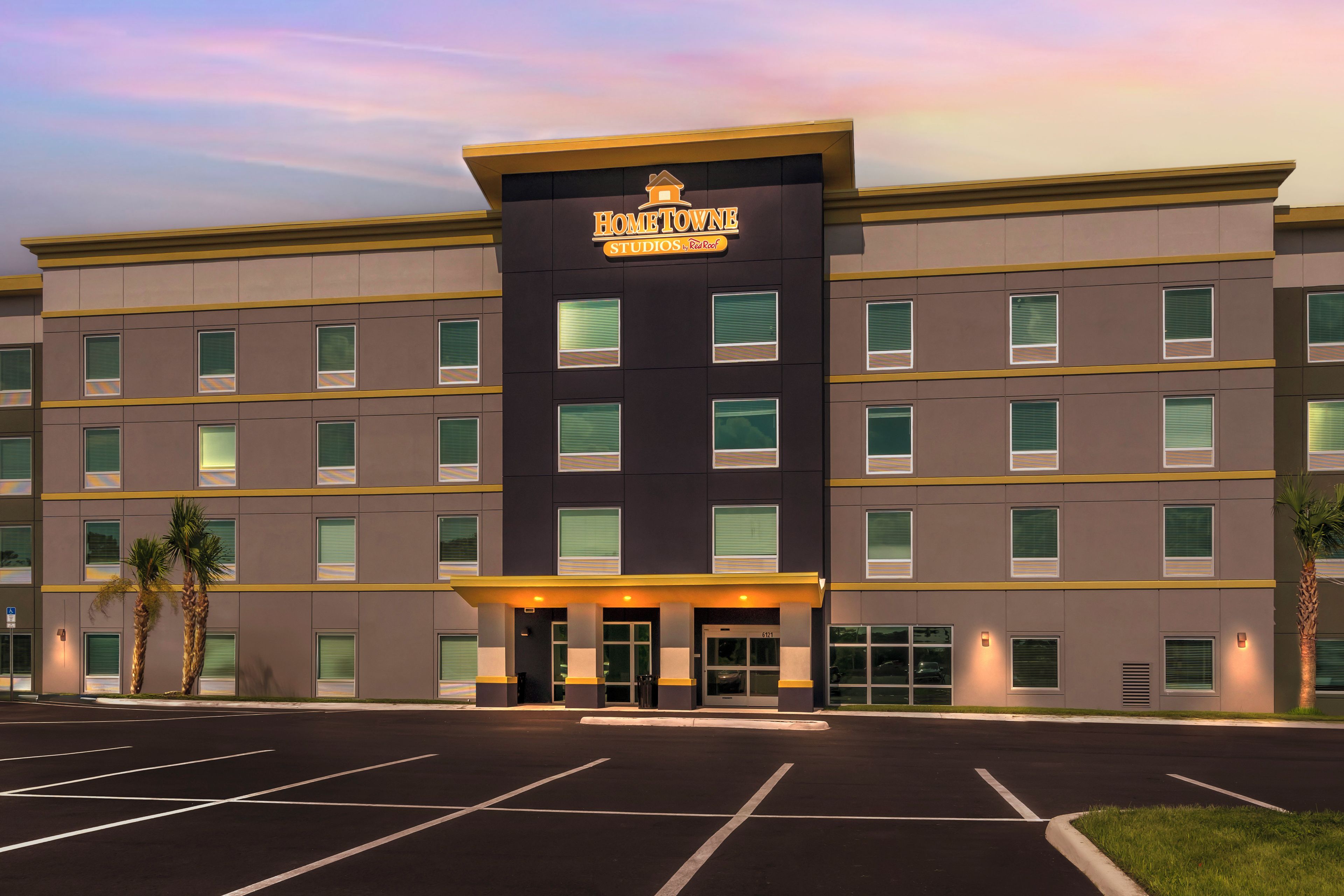 A multi-story hotel with a prominent entrance and a parking lot in front.