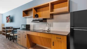 A modern kitchen with wooden cabinets, a black refrigerator, a microwave, and a coffee maker.