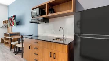 Una cocina moderna con un refrigerador negro, gabinetes de madera, un lavamanos de acero inoxidable y un microondas.