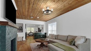 A spacious living room with a fireplace, a wooden ceiling, and a dining area in the background. - Downtown Denison Dream (Denison)
