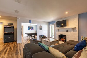 A living room with a fireplace, a television mounted on the wall, and a pool table. - Lakefront Retreat w/Pvt Dock, Game Room, Hot Tub (Murray)