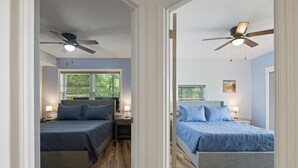 A bedroom with two beds, wooden flooring, ceiling fans, and bedside lamps. - Lakefront Retreat w/Pvt Dock, Game Room, Hot Tub (Murray)